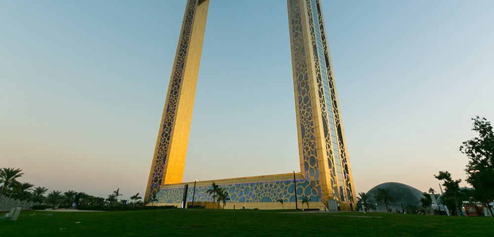 Dubai Sightseeing City Tour Combo Dubai Frame at day light and IMG Worlds of Adventure roaring dinosaur at night