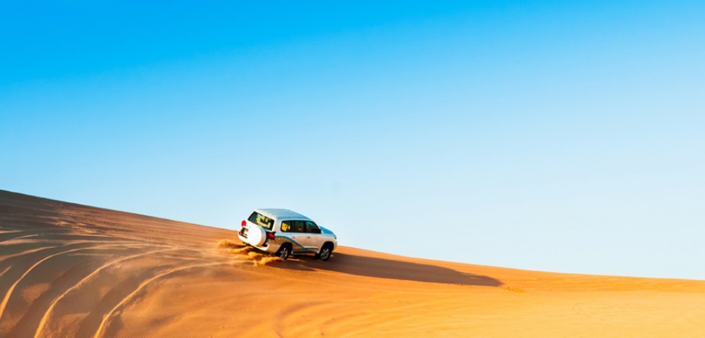 “A desert safari combo with a vehicle driving on the desert and Abu Dhabi City Tour combo  with tall buildings in the background”
