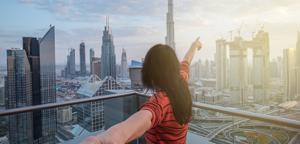 Dubai Sightseeing City Tour, a woman pointing to Burj Khalifa and Cruise Combo Deals Creek at night