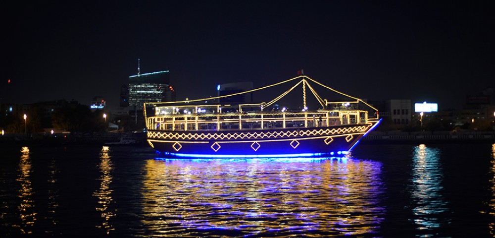 Dubai Sightseeing City Tour, a woman pointing to Burj Khalifa and Cruise Combo Deals Creek at night