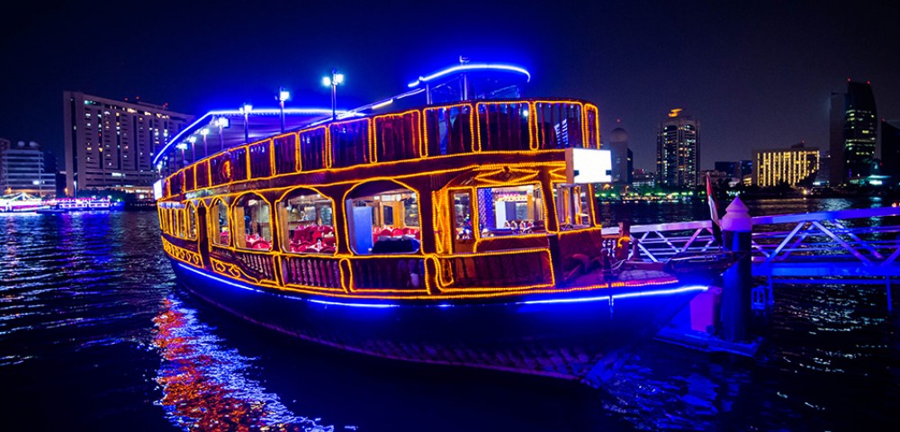 Dubai Sightseeing City Tour, a woman pointing to Burj Khalifa and Cruise Combo Deals Creek at night